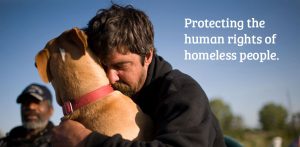 an image of a man sitting outdoors holding his dog closely in a loving embrace